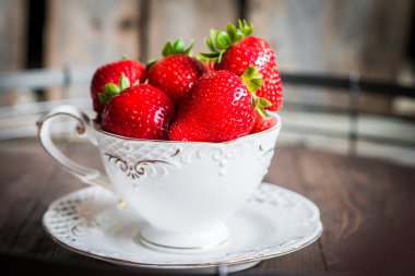 Ahşap arka plan üzerine bir fincan taze çilek