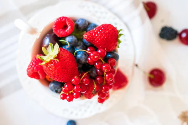 Mix of fresh berries in a cup of tea — Stock Photo, Image