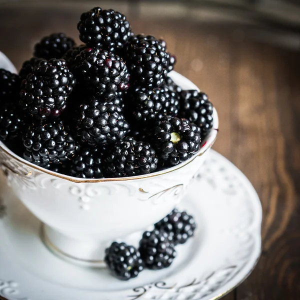 Blackberries in a mug on wooden background — Stock Photo, Image