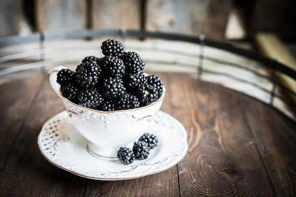 Blackberries in a mug on wooden background — Stock Photo, Image