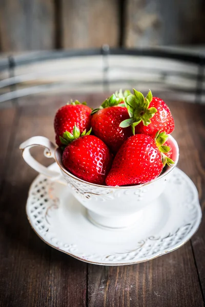 Fresh strawberries in a cup on wooden background — Stock Photo, Image