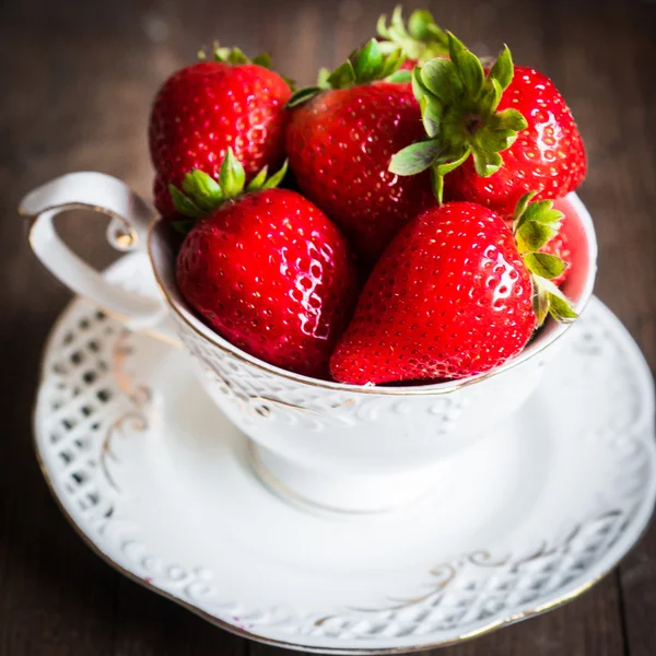 Fresh strawberries in a cup on wooden background — Stock Photo, Image