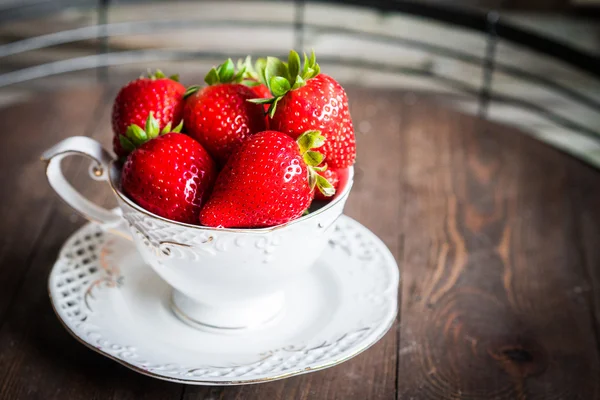 Fresh strawberries in a cup on wooden background — Stock Photo, Image