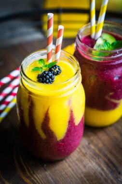 Mango ve rustik wo üzerinde meyveleri ile renkli iki katman smoothies