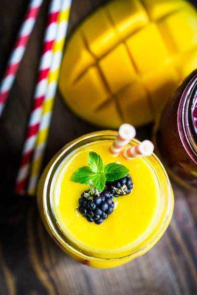 Bunte zweischichtige Smoothies mit Mango und Beeren auf rustikalem — Stockfoto