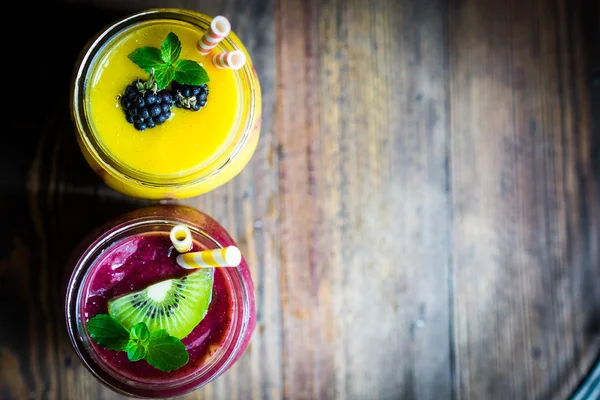 Colorful two layer smoothies with mango and berries on rustic wo — Stock Photo, Image