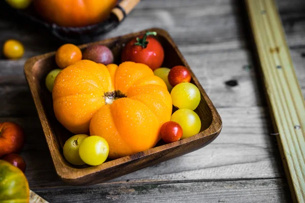 Fargerike arvetomater med jordbruksbakgrunn av tre – stockfoto