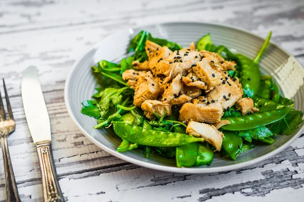 Жареная курица со шпинатом, рукколой и горохом на деревенском деревянном b — стоковое фото