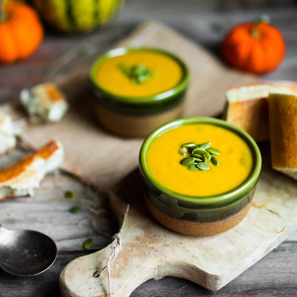 Cremige Kürbissuppe mit Kernen auf Holzgrund — Stockfoto