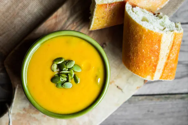 Вершковий гарбузовий суп з насінням на дерев'яному фоні — стокове фото