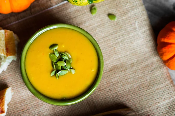 Cremige Kürbissuppe mit Kernen auf Holzgrund — Stockfoto