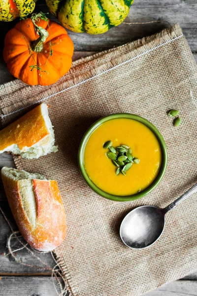 Cremige Kürbissuppe mit Kernen auf Holzgrund — Stockfoto