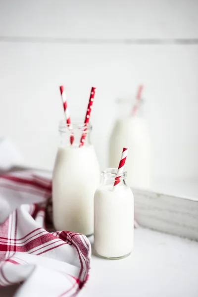 Milk jar with red striped straws on white wooden background — Stock Photo, Image