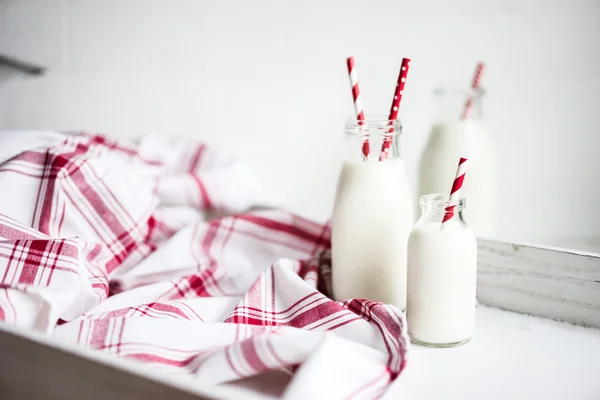 Milk jar with red striped straws on white wooden background — Stock Photo, Image