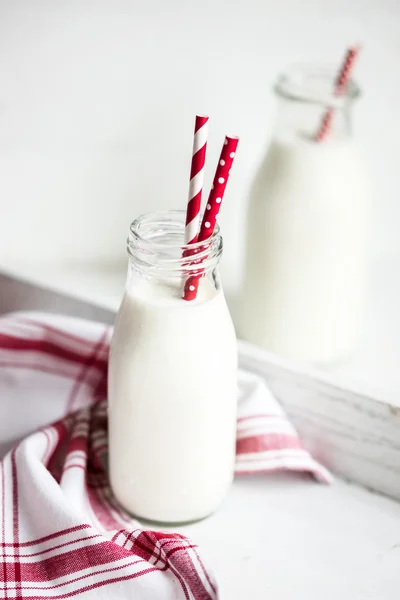 Milk jar with red striped straws on white wooden background — Stock Photo, Image