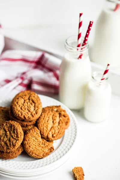 Biscotti di farina d'avena con latte in barattoli su fondo di legno bianco — Foto Stock