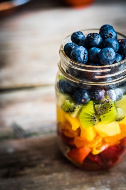 Bir kavanoza rustik ahşap arka plan üzerinde renkli meyve salatası