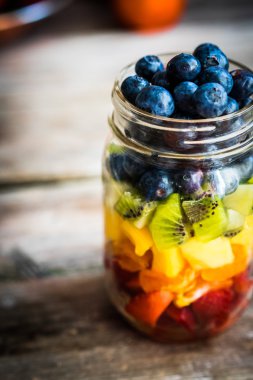 Bir kavanoza rustik ahşap arka plan üzerinde renkli meyve salatası