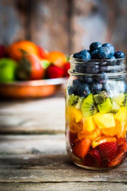 Bir kavanoza rustik ahşap arka plan üzerinde renkli meyve salatası