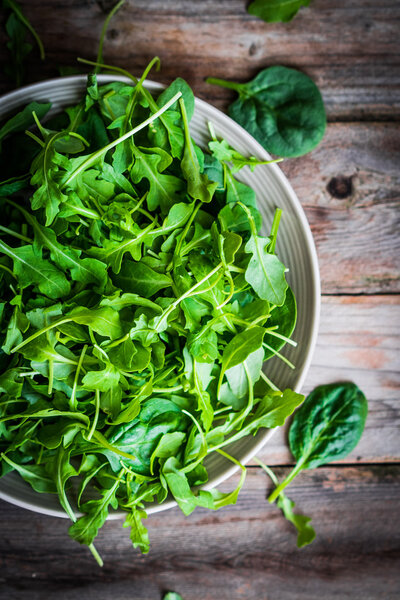 Fresh arugula and spinach salad on rustic background