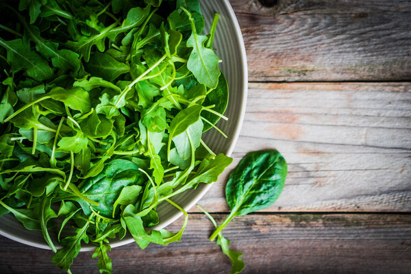 Fresh arugula and spinach salad on rustic background