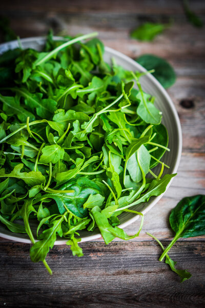 Fresh arugula and spinach salad on rustic background
