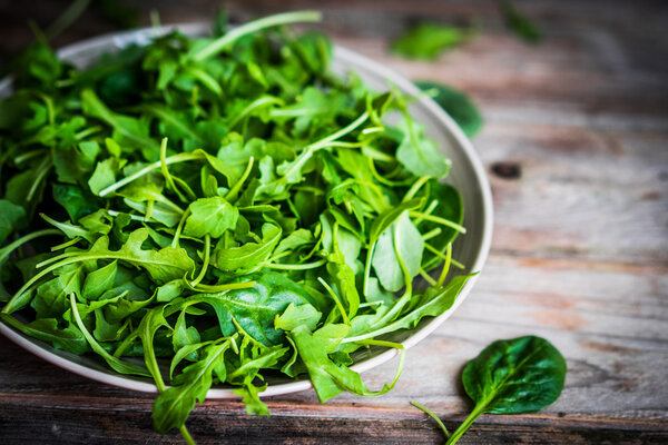 Fresh arugula and spinach salad on rustic background
