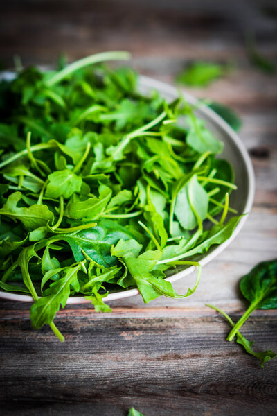 Fresh arugula and spinach salad on rustic background