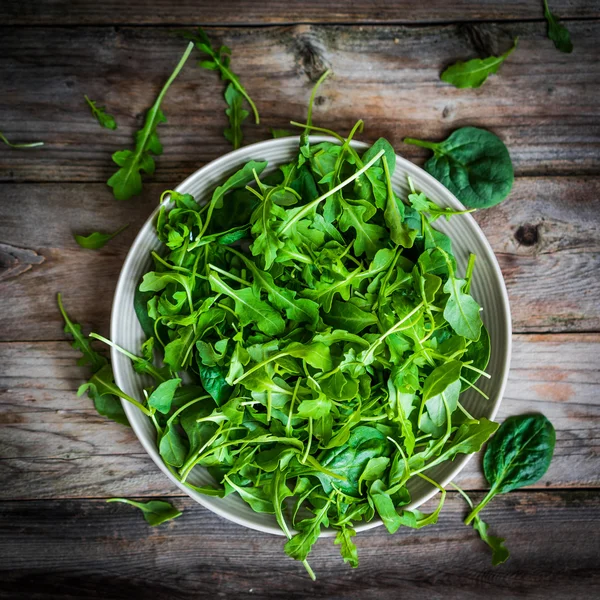 Frischer Rucola und Spinatsalat auf rustikalem Hintergrund — Stockfoto