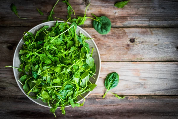 Свежий салат из рукколы и шпината на деревенском фоне — стоковое фото