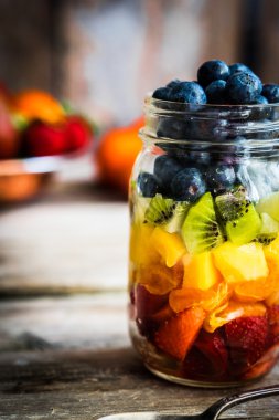 Bir kavanoza rustik ahşap arka plan üzerinde renkli meyve salatası