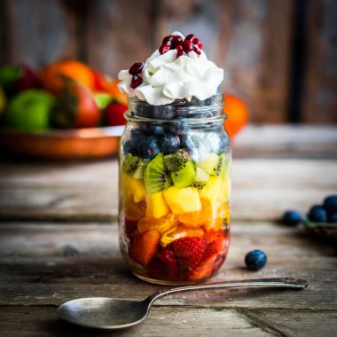 Bir kavanoza rustik ahşap arka plan üzerinde renkli meyve salatası