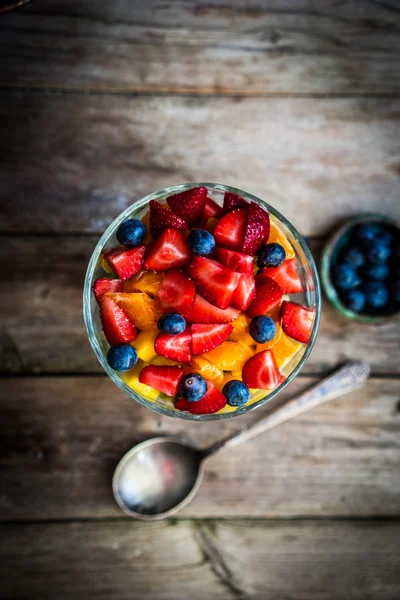 Colorful fruit salad in a jar on rustic wooden background — Stock Photo, Image