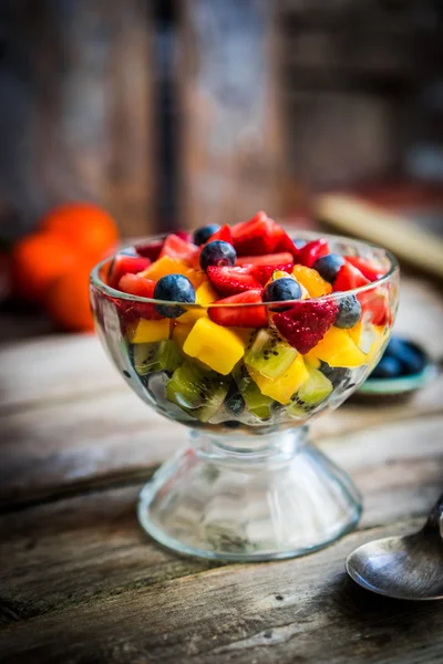 Ensalada de frutas coloridas en un frasco sobre fondo rústico de madera — Foto de Stock