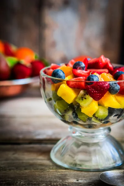 Salada de frutas colorida em um frasco em fundo de madeira rústica — Fotografia de Stock