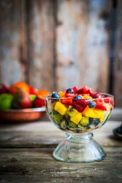 Barevný ovocný salát ve sklenici na rustikální dřevěné pozadí — Stock fotografie