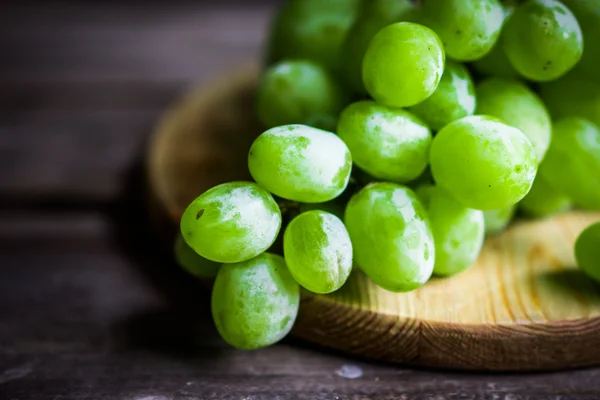 Vine of green grapes on rustic wooden background — Stock Photo, Image