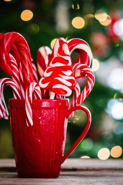 Candy canes in red mug on wooden background — Stock Photo, Image