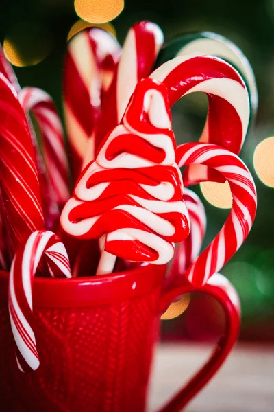 Candy canes em caneca vermelha no fundo de madeira — Fotografia de Stock