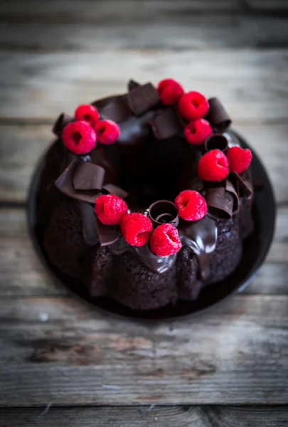 Bolo de chocolate com framboesas em fundo de madeira rústica — Fotografia de Stock