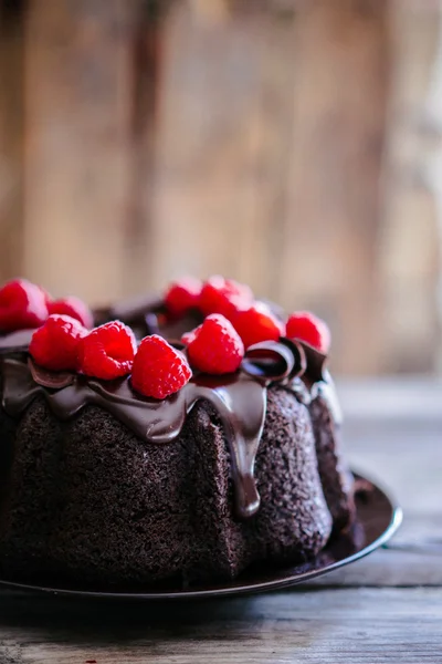 Pastel de chocolate con frambuesas sobre fondo rústico de madera — Foto de Stock