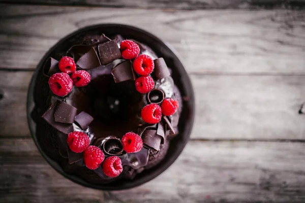 Bolo de chocolate com framboesas em fundo de madeira rústica — Fotografia de Stock