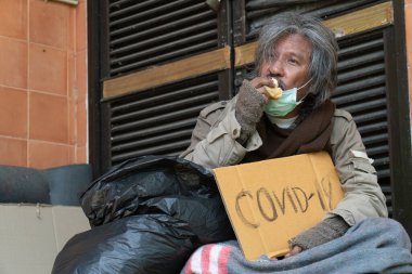 Evsiz bir adam cvid-19 işareti taşıyor, modern megacities problemi..