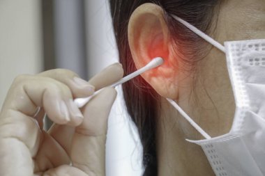 Kadın kulaklarını pamukla temizliyor..