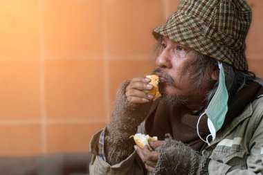 Evsiz ve aç. Ekmek yiyen kıdemli adama yaklaş..