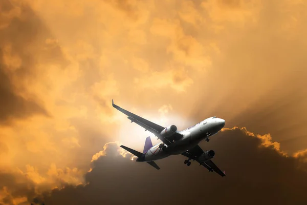 Uçak dramatik gökyüzü ile alacakaranlıkta uçar.