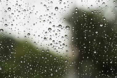 Yol arkaplanlı pencere camları üzerinde yağmur damlaları .