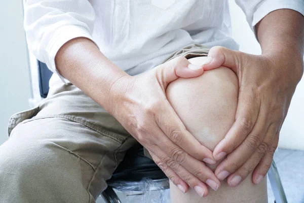 Diz eklemlerine dokunan, acı çeken bir kadın. Eklem iltihabı, kemik hastalığı osteoporoz veya iltihaplanma süreçleri.