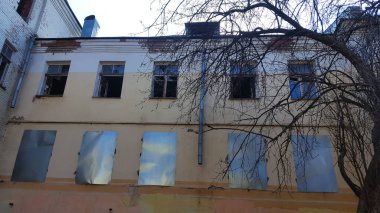 Şehir merkezinde gökyüzüne karşı terk edilmiş eski toprak binanın ağaç, duvar ve penceresi.