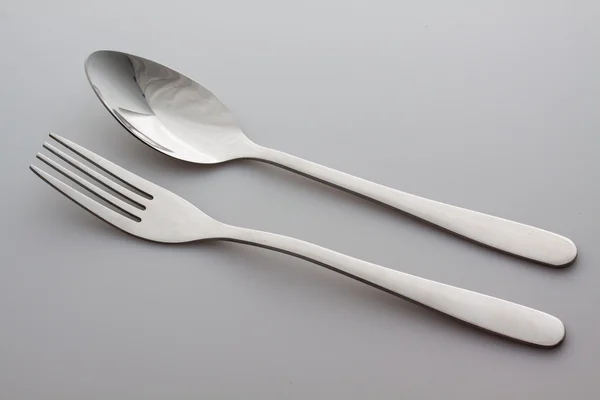 Een zilveren vork met lepel geïsoleerd op grijze achtergrond — Stockfoto